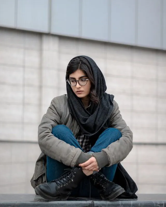 Woman with scarf looking down sad